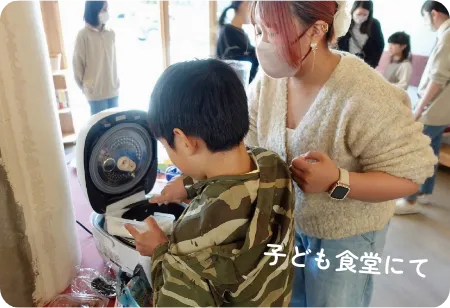 子ども食堂にて。炊飯器からご飯をつぐ子どもとの画像